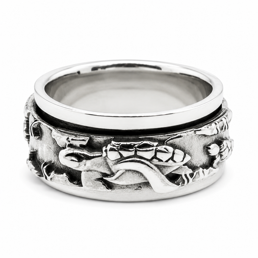 A sterling silver spinner ring featuring an embossed design of sea turtles and marine life on the band, shown on a clean white background.