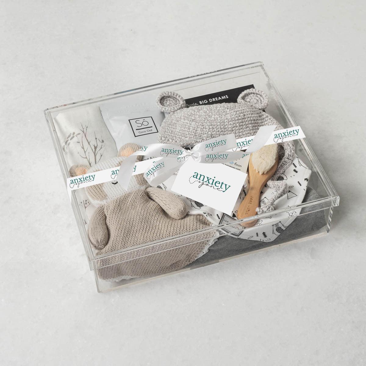 Baby Bear Gift Box – Premium new baby gift basket featuring a crochet knit toque with bear ears, cotton onesie, goat brush, forest-patterned swaddle, plush panda, coconut & oat milk bath, and classic "Brown Bear, Brown Bear" book. Ideal for baby showers, birthdays, or gender-neutral gifts for a newborn.