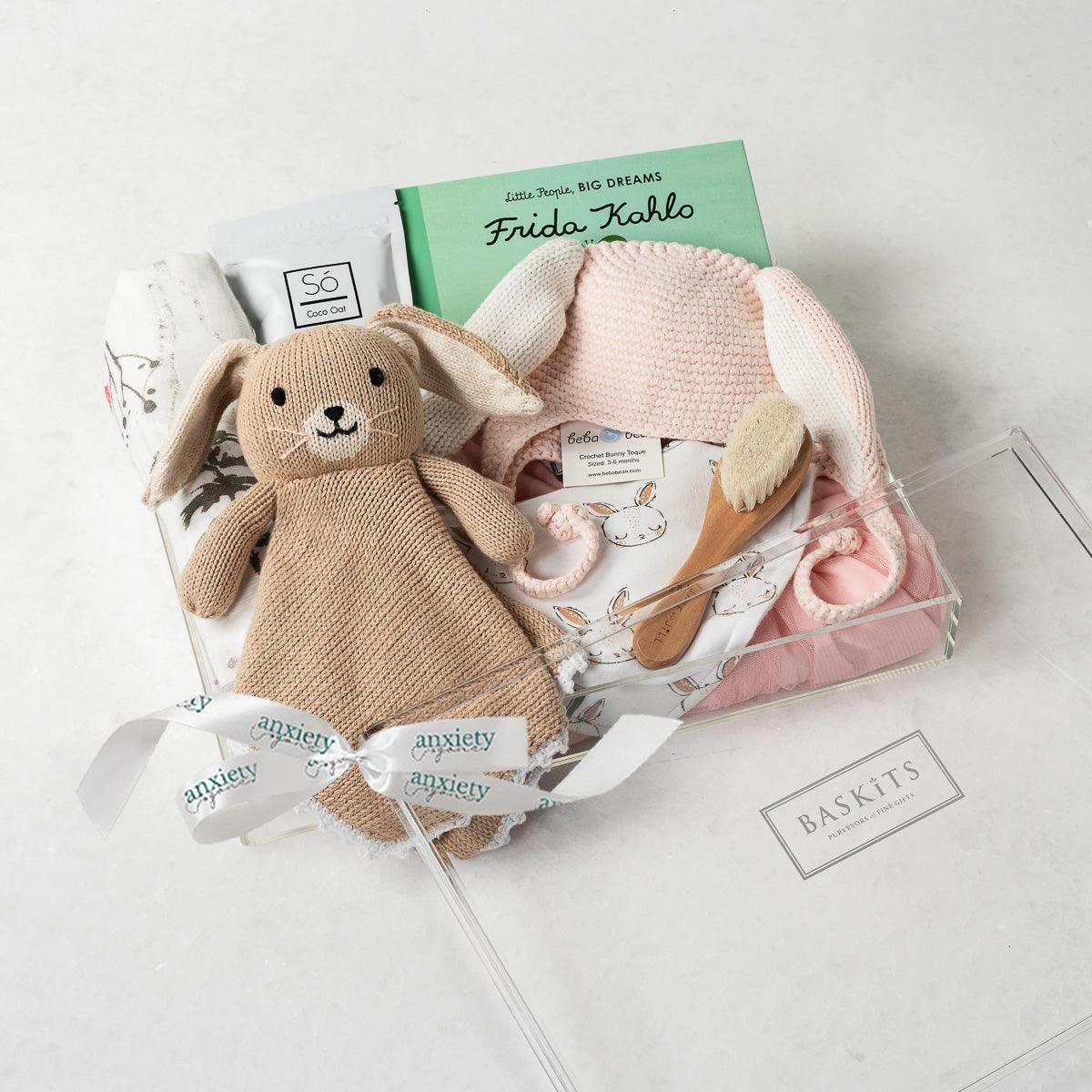 Little Bunny Gift Box – Unique baby gift basket with personalized baby gifts, including a pink tutu dress, gender-neutral baby items, custom newborn gifts, baby shower gift, baby girl gifts, forest-patterned swaddle, Bailey the Bunny Lovie, coconut & oat milk bath, and Frida Kahlo book. Perfect new baby gift basket for welcoming a newborn with thoughtful and charming baby boy or girl gifts.