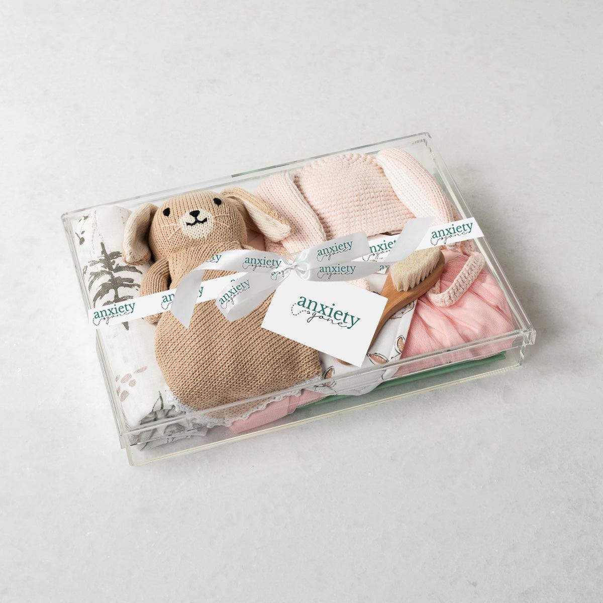 Little Bunny Gift Box – Unique baby gift basket with personalized baby gifts, including a pink tutu dress, gender-neutral baby items, custom newborn gifts, baby shower gift, baby girl gifts, forest-patterned swaddle, Bailey the Bunny Lovie, coconut & oat milk bath, and Frida Kahlo book. Perfect new baby gift basket for welcoming a newborn with thoughtful and charming baby boy or girl gifts.