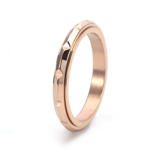 Close-up of raised triangular points on a stainless steel anxiety ring in rose gold