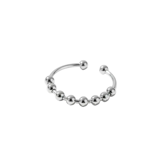 A polished silver open fidget ring decorated with a row of small metallic beads, photographed on a clean white surface with soft shadows.